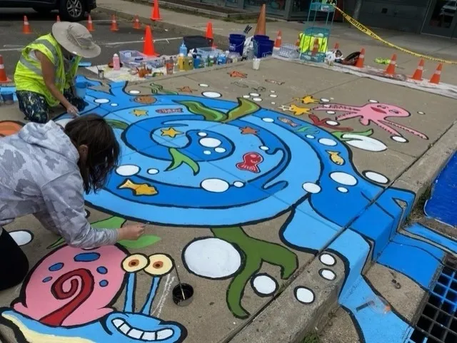 A group of people painting on the ground.