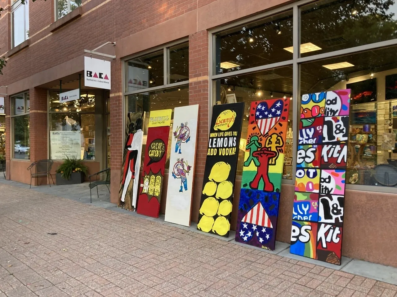 A row of colorful paintings on display outside.