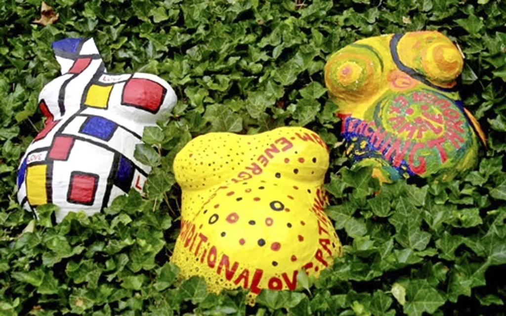 A group of colorful sculptures sitting in the grass.