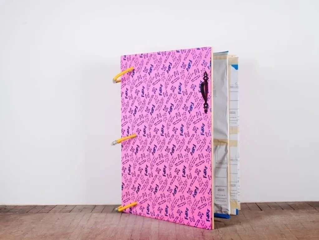 A pink book with some paper on top of it