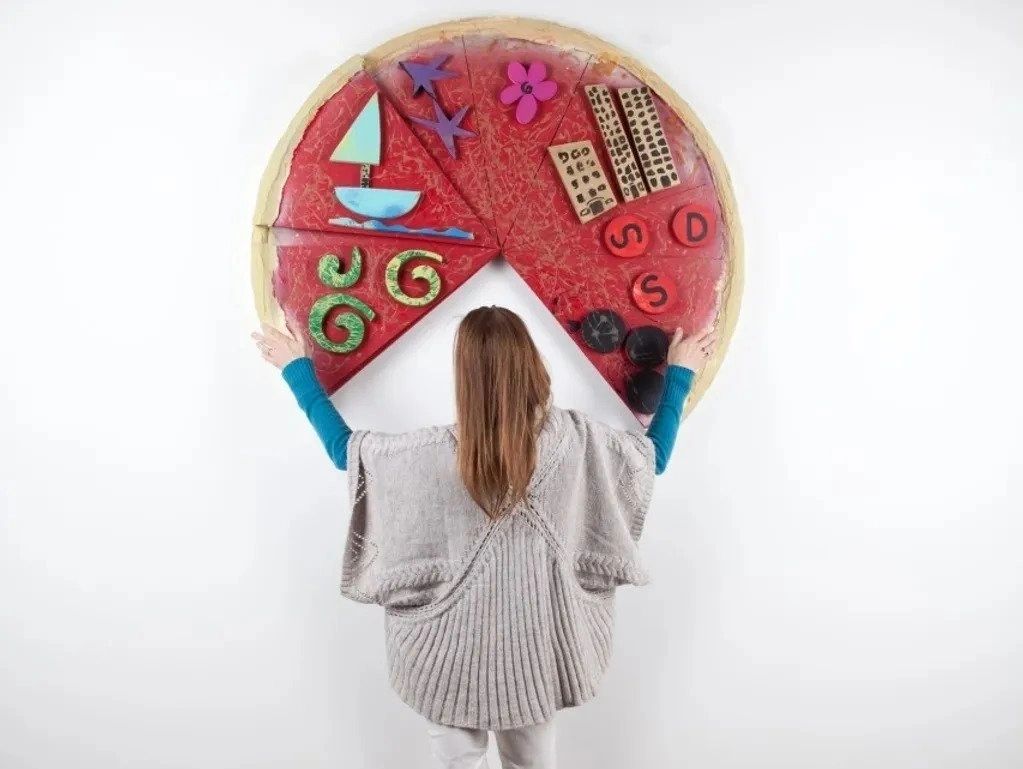 A woman holding up a pizza with many different toppings.