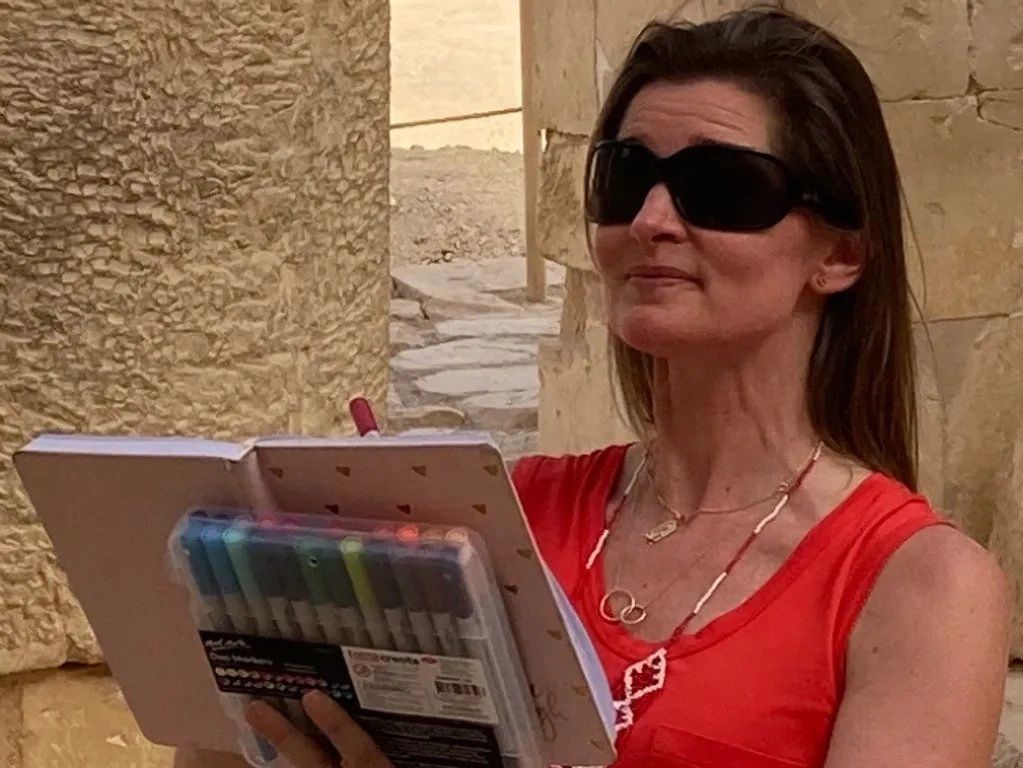 A woman in sunglasses holding an open book.