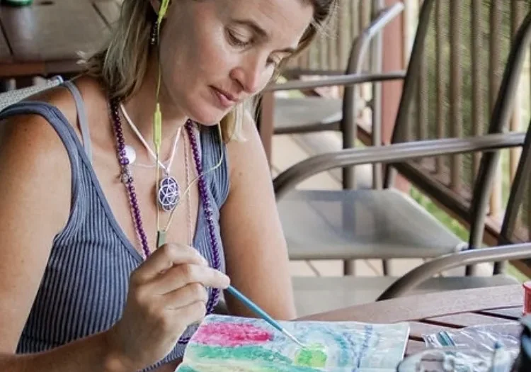 A woman painting with watercolors on top of a table.