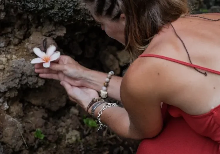 A woman kneeling down holding a flower in her hand.
